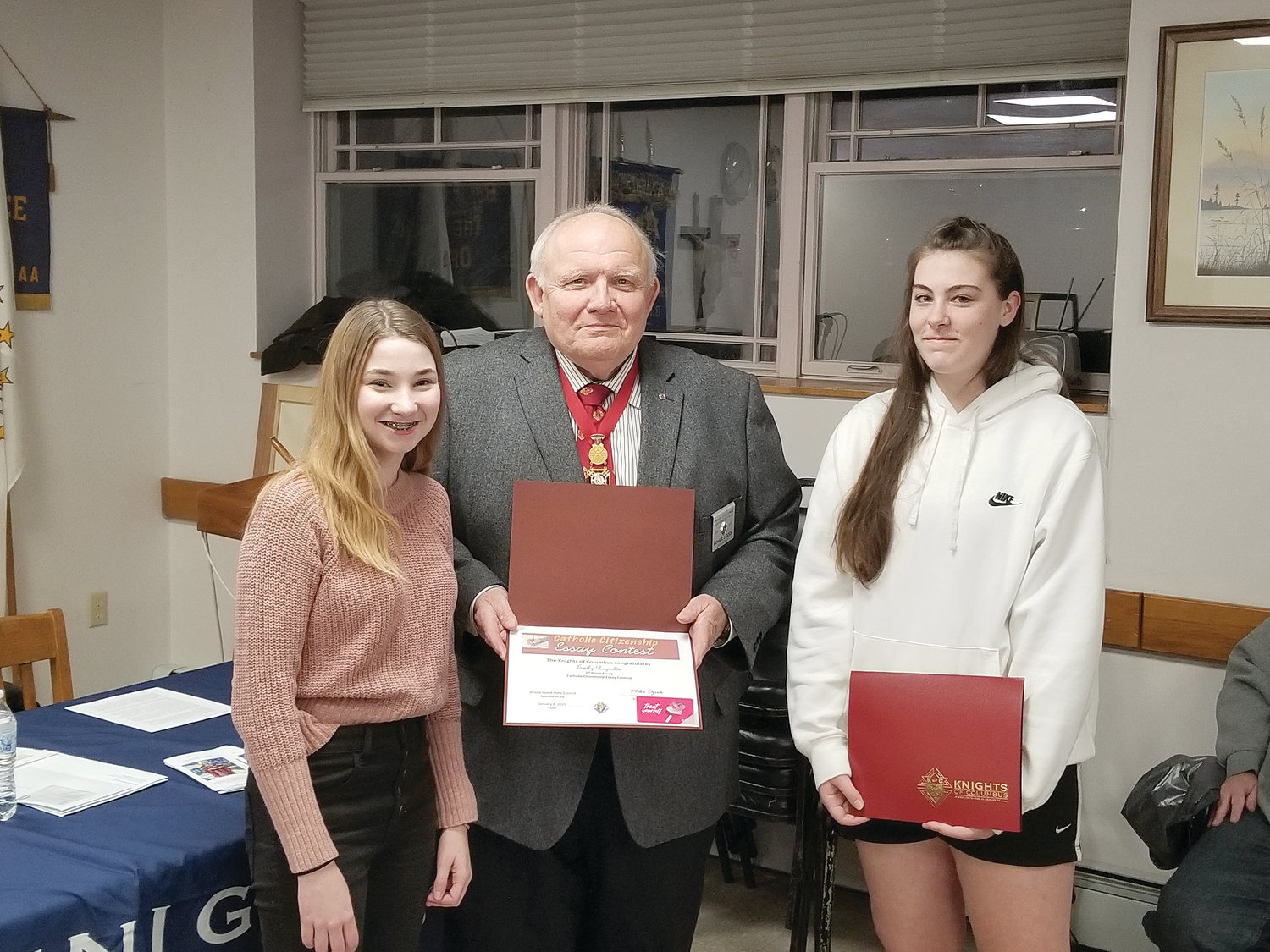 Knights of Columbus State Deputy Grand Knight Mike Dziok presents award certificates to Emily Reynolds and Julia Rensehausen for their submissions in the Catholic Citizenship Essay Contest. The essays have been sent to Supreme Council for judging at the International Contest level.